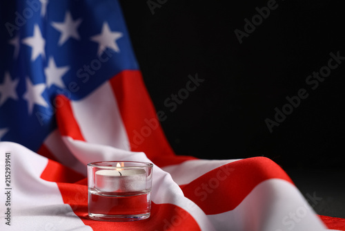 Canvas Print Lit candle in glass holder on draped United States flag, memorial day and rememb