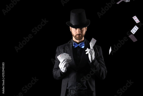 Fotografie Male magician with playing cards on black background