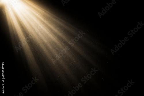 Golden light beam with dust particles isolated on black background, abstract light effect, spotlight, sun rays, lens flare, overlay