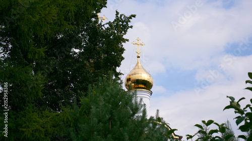 Konstfotografi Golden onion dome and ornate Orthodox cross rising above lush evergreen trees be