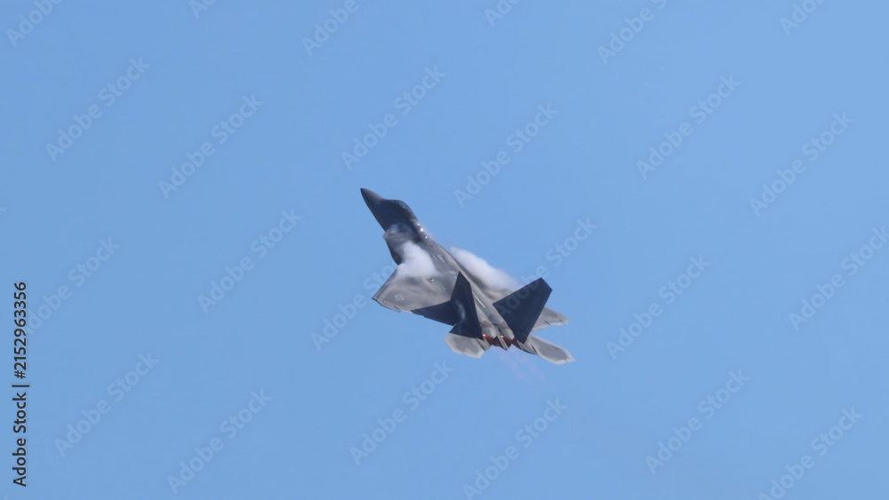 Obraz premium F-22 Raptor Fighter Jet Performing High-Speed Maneuver in Blue Sky