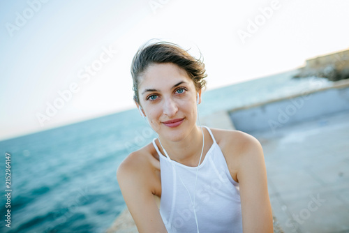 Foto Portrait of young woman looking at camera with headphones with sea background