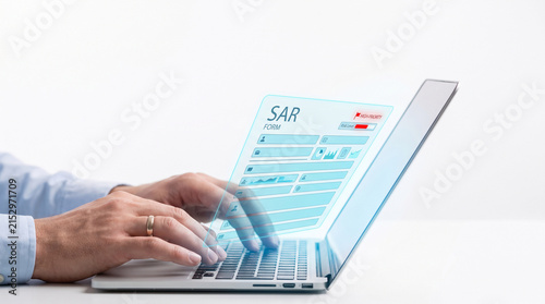 Professional compliance officer typing a Suspicious Activity Report SAR on a laptop computer representing modern RegTech solutions for financial crime prevention and regulatory compliance.
