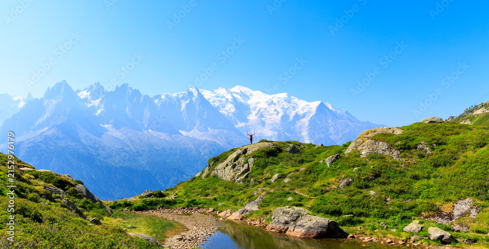 Obraz premium Hiker standing on mountain ridge with raised arms facing Mont Blanc snow peaks alpine landscape success freedom