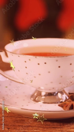 Animation of glowing stars falling over cup of tea with christmas cookies