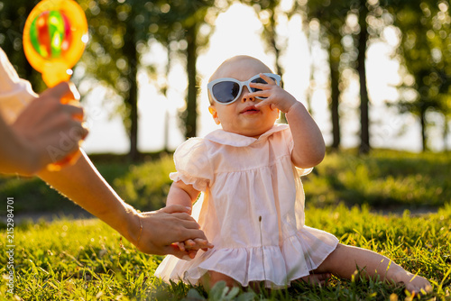 Adorable baby wearing sunglasses and a cute dress in a sunny park