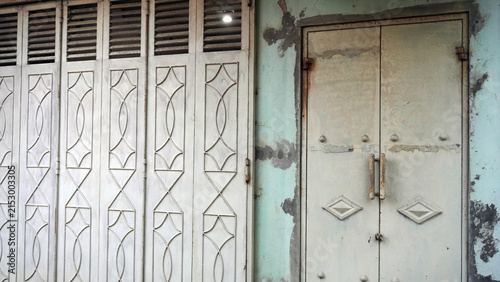 Old weathered metal folding shutter doors with decorative pattern.