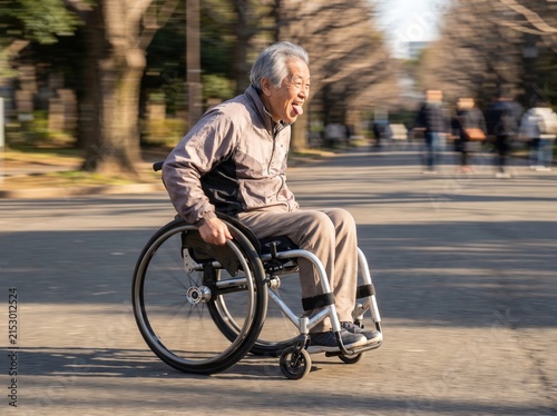 An active senior man uses his personal wheelchair to travel fast through a city park during the sunny afternoon while enjoying the motion and feeling liberated from his physical mobility