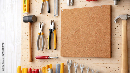 Cork board with hand tools including hammer, pliers, wrench, and screwdriver on pegboard