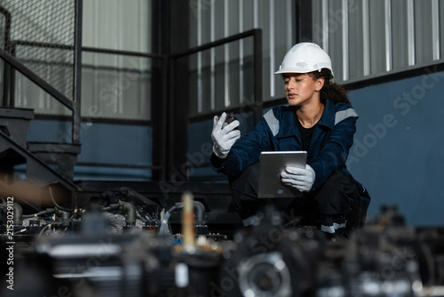 Professional female engineer in a hard hat using a digital tablet to inspect electronic waste and machinery parts for sustainable Industry 4.0 automation and e-waste recycling solutions.