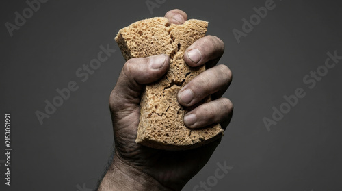 Economic struggle recession concept with hand squeezing dry sponge symbolizing hardship and scarcity
