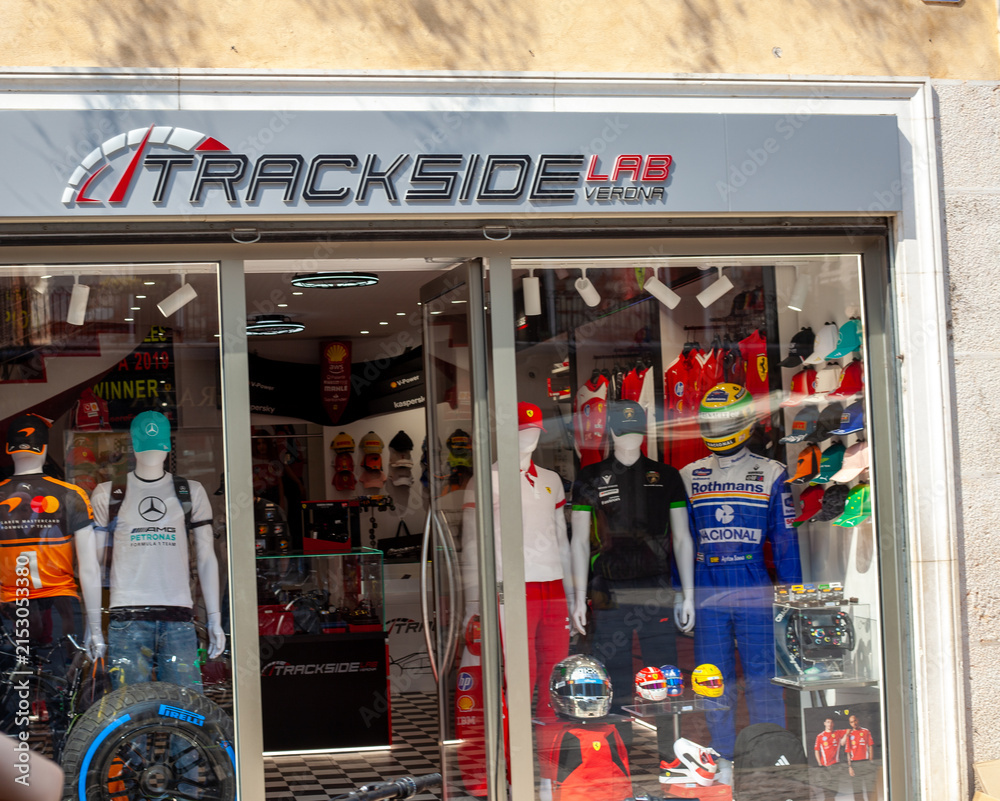Fototapeta premium Window shop Trackside Lab Storefront with Formula 1 Racing Merchandise store Display in Old Town street. Verona, Italy - June 25, 2026
