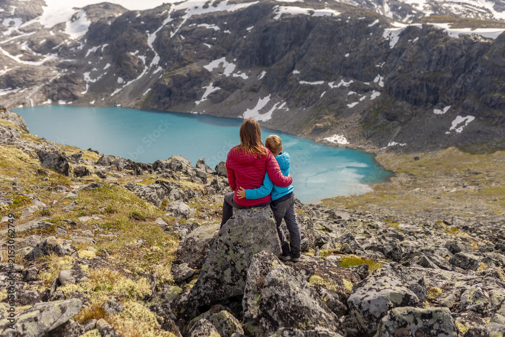 Fototapeta premium Beautiful european family with children and pet dog, hiking Kyrkja mountain on a beautiful sunny summer day, sunset, snow, lakes, valley