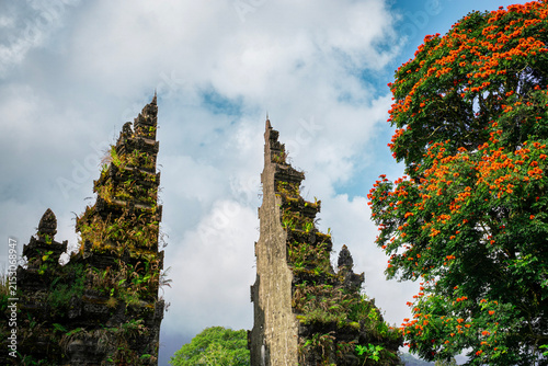 Fotografía Traditional Balinese Candi Bentar Temple Gate with Blooming Flame Tree in Bali I