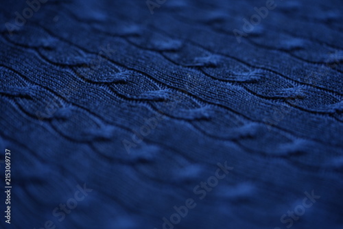 Blue cable knit fabric texture background Close-up texture of dark blue knitted fabric with classic cable knit pattern. Soft cozy textile surface with detailed stitches, ideal for winter fashion, swea