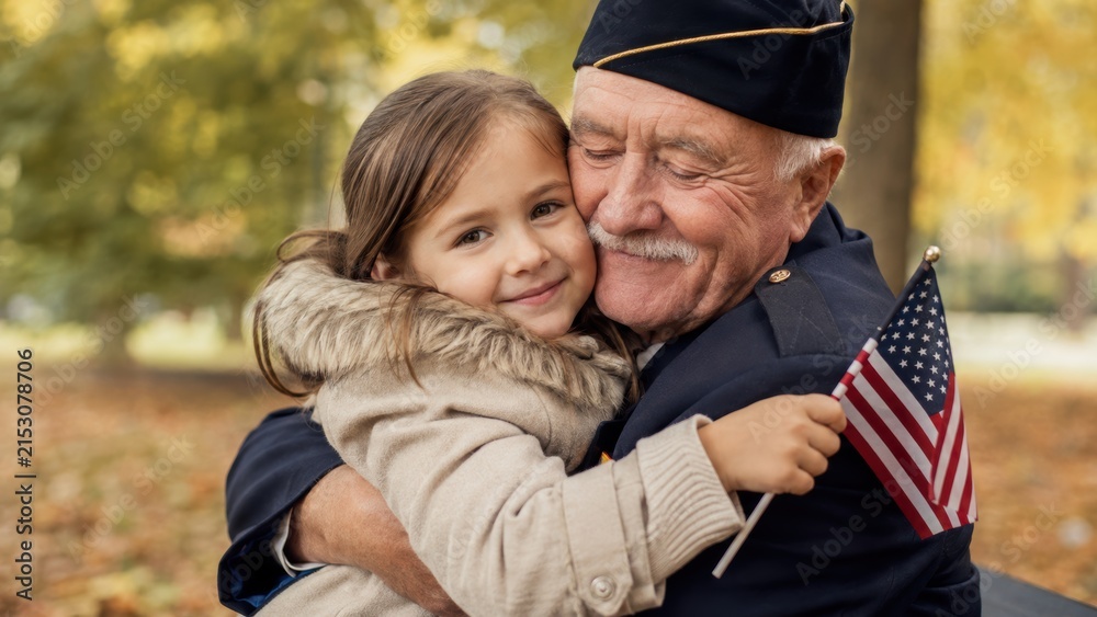 Fototapeta premium elderly military veteran grandfather hugging his young granddaughter holding a small american flag in an autumn park