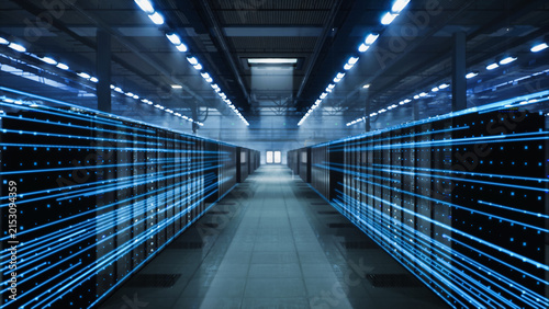 Symmetrical Perspective Down a Data Center Aisle as Bright Blue Fiber Optic Light Trails Shoot Along Towering Server Cabinets Under Ceiling Strip Lamps, Depicting Rapid Network Traffic.
