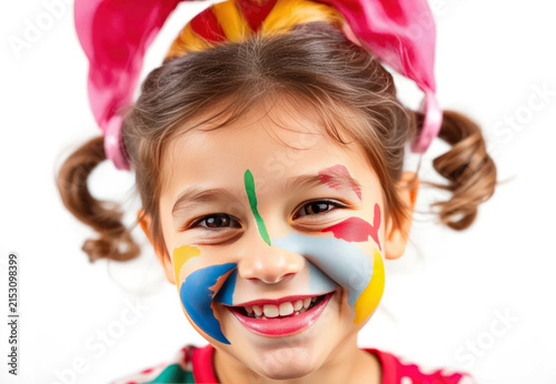 Joyful young girl with colorful face paint and playful hairstyle smiling brightly against a white background in a fun and cheerful atmosphere