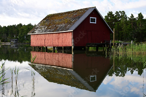 Bild auf Leinwand Red boathouse reflected in calm lake water