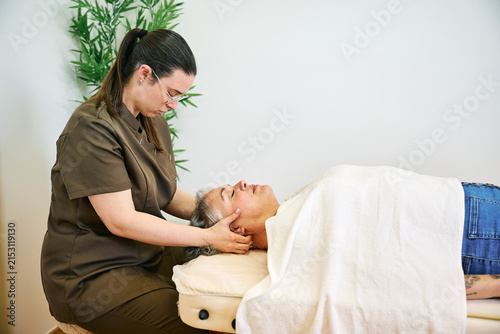 Therapist providing head and neck massage to woman
