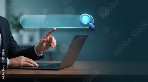 A business professional using a laptop to perform an online search with a digital magnifying glass icon interface overlay