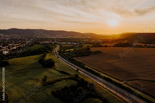 Golden hour aerial landscape with winding highway and sunflower fields near Saalfeld