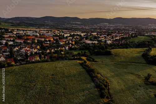 Aerial view of a German town named Gorndorf nestled behind sunflower fields at sunset