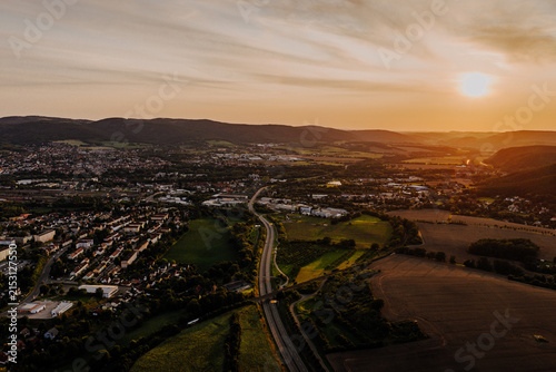 Spectacular aerial sunset landscape with a curving highway and rural town named Saalfeld