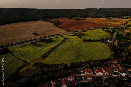 Aerial view of a vast sunflower field and rural highway at sunset near Saalfeld