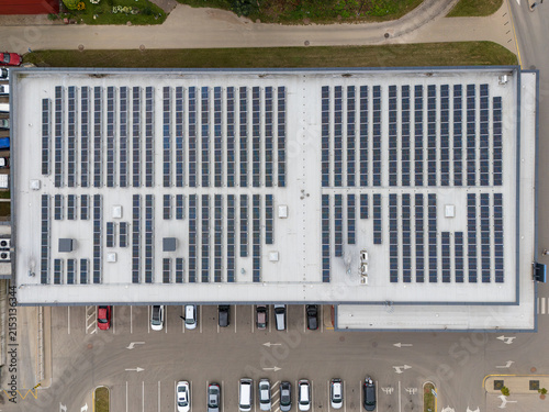 Aerial top-down view of large commercial building rooftop covered with solar panels, renewable energy and sustainable business infrastructure concept.