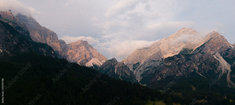 Obraz premium Aerial vertical shot of a mountain ridge featuring sharp rock formations, lush green meadows, and expansive scenic vistas 