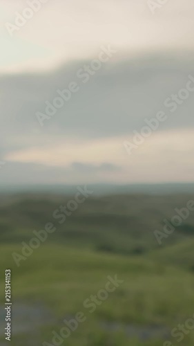 Young woman stands on a hill in indonesia, watching the sunset over lush green hills, painting the sky with orange and pink hues