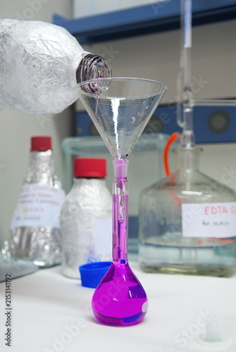 Foto Versamento di liquido chimico viola in un matraccio tarato attraverso un imbuto