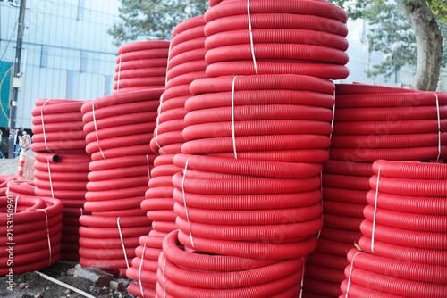Stacks of red corrugated pipes at a construction site