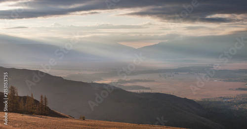 Mountain valley in the morning light, cloudy sky, sun rays