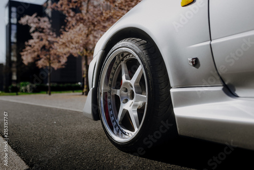 Detail shot of a silver custom rim with red brake calipers on a tuned Japanese sports car