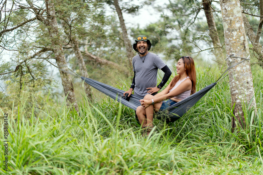 Obraz premium Asian couple relaxing together in a hammock surrounded by lush tropical nature