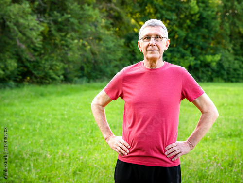 Senior man exercising outdoors in a green park and enjoying an active healthy lifestyle. Copy space.