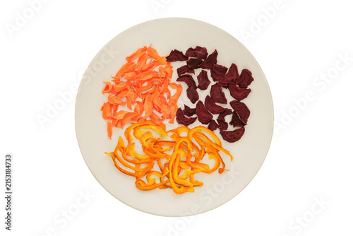 Top view. Freeze-dried vegetable for travel. Dried beetroot, sweet pepper and carrot on a ceramic plate isolated on a white background. Various dry of vegetables.