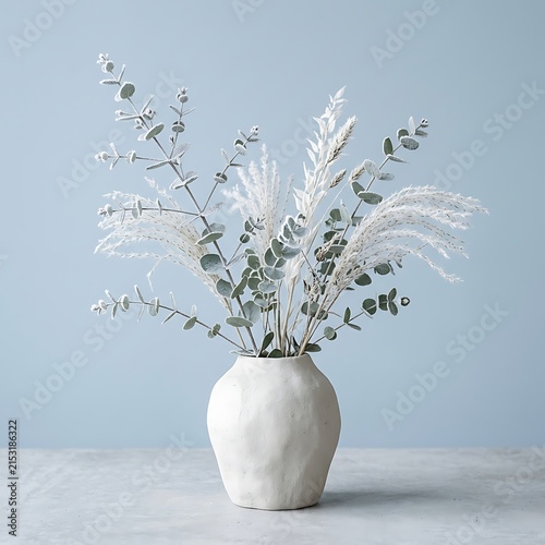 Elegant dried flower arrangement in minimalist white vase on light surface