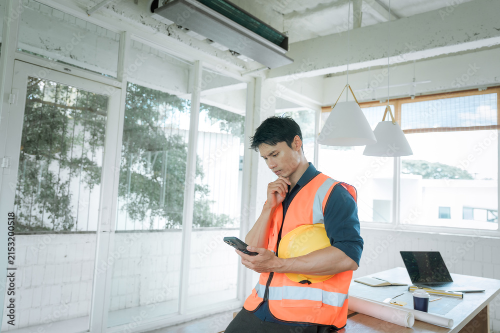 Fototapeta premium Construction worker in a safety vest holding a hard hat and looking stressed at a building site, representing workplace pressure, construction challenges and project management.