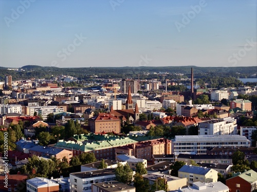Aerial view of Tampere Cathedral and the surrounding urban skyline with historic buildings, rooftops, and lush greenery in Tampere, Pirkanmaa, Finland.