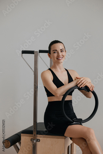 Woman holding Pilates ring while sitting on chair in fitness studio