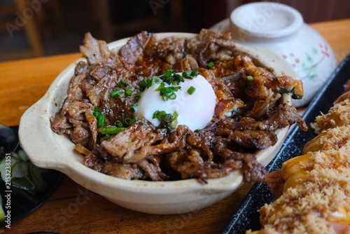 Konstfotografi Closeup of nikudon, a Japanese beef rice bowl topped with a soft egg and chopped herbs, served on a dining table
