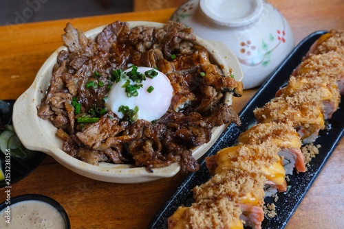 Canvastavla Close-up of nikudon, a Japanese beef rice bowl topped with egg, served alongside salmon sushi in a restaurant setting