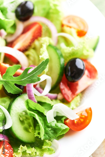 Salad with Olives, Tomatoes and Cucumber on wooden Background. Healthy Snack Idea. Close up