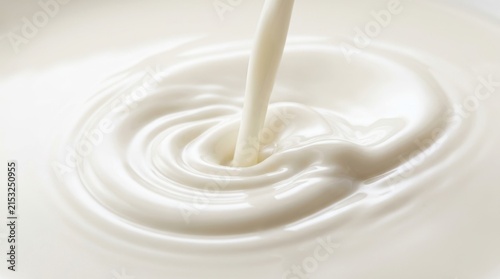 Fresh white milk pouring into a bowl creating smooth concentric circular ripples and soft shadows