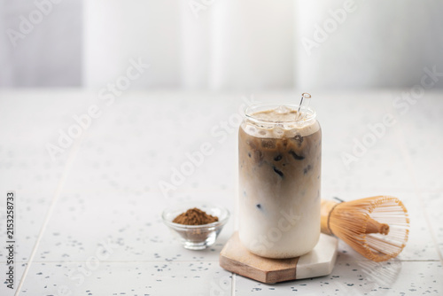 Refreshing cold iced hojicha tea latte in a tall glass, perfect for a summer day. Copy space