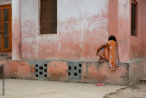 AYODHYA, INDIA - OCT 2019: A woman rests in the corner of a weathered building
