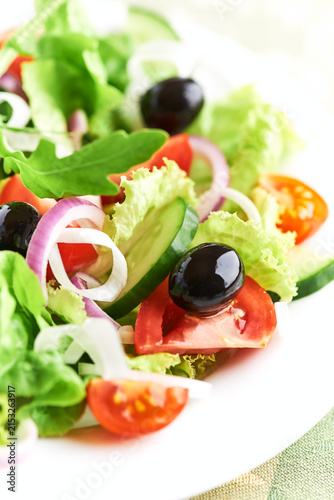 Salad with Olives, Tomatoes and Cucumber on wooden Background. Healthy Snack Idea. Close up